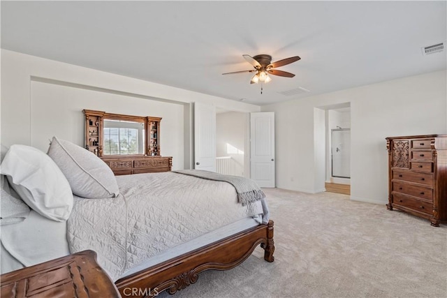 bedroom with visible vents, ensuite bathroom, a ceiling fan, and light colored carpet