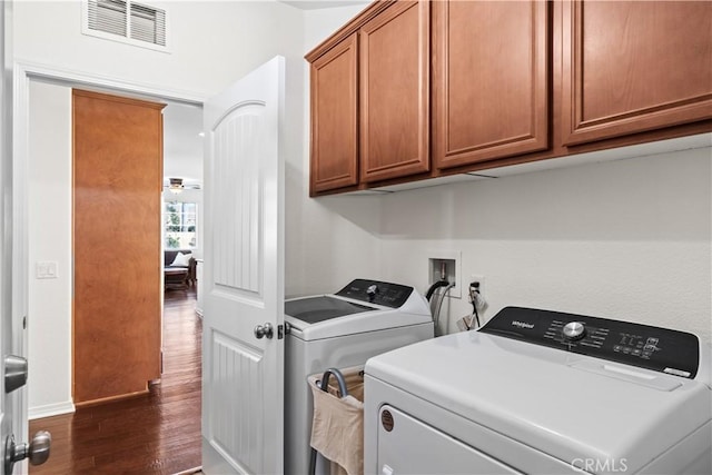 laundry room with dark wood-style flooring, visible vents, cabinet space, and washing machine and clothes dryer