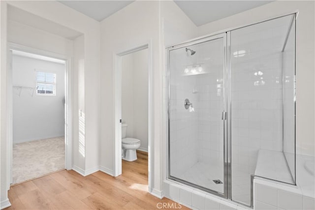 full bath with wood finished floors, a shower stall, toilet, and baseboards