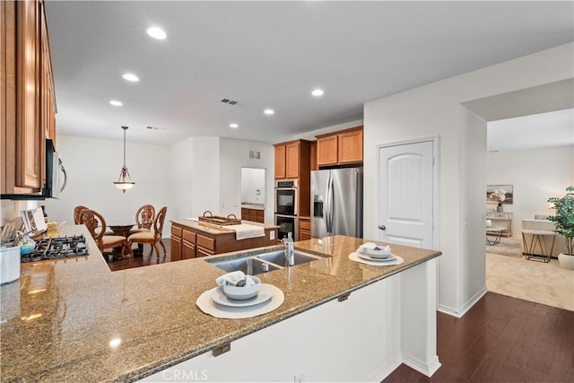 kitchen featuring stone countertops, a sink, visible vents, appliances with stainless steel finishes, and brown cabinets