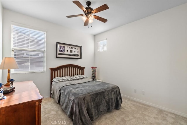 bedroom with a ceiling fan, light carpet, and baseboards