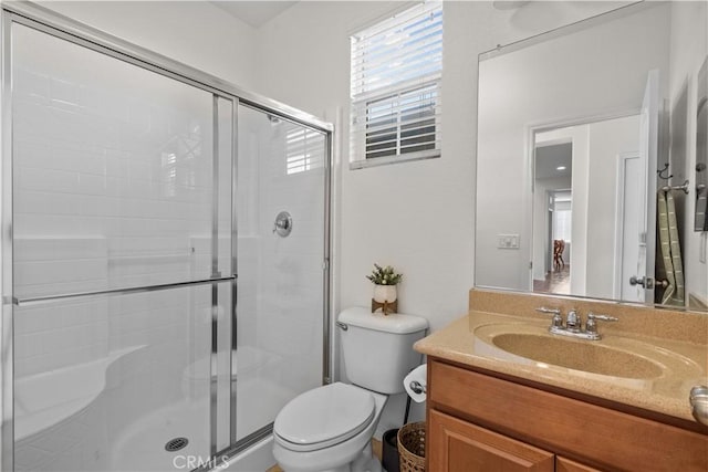 bathroom with a stall shower, vanity, and toilet