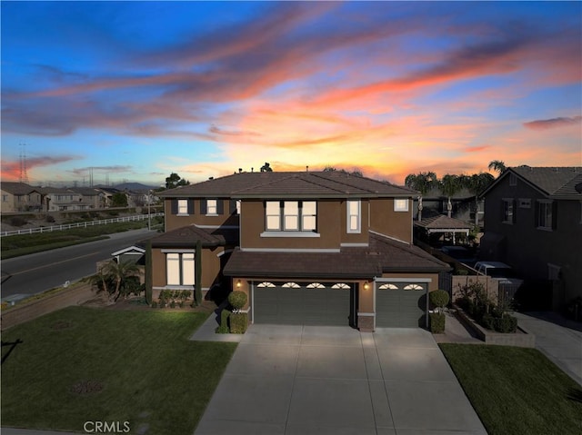 view of front of home with stucco siding, concrete driveway, a lawn, a garage, and a tiled roof