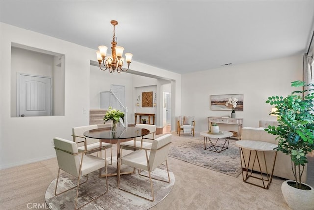 dining room with a chandelier, baseboards, visible vents, and light colored carpet