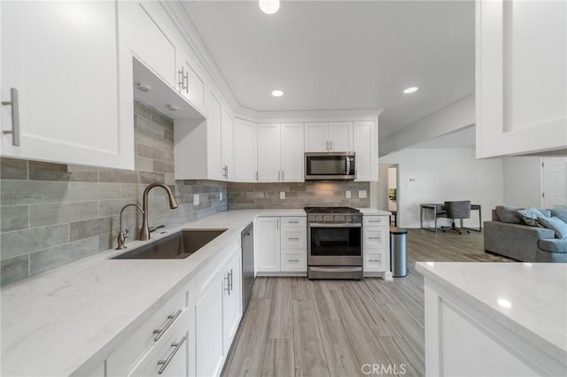 kitchen with stainless steel appliances, white cabinetry, sink, and tasteful backsplash