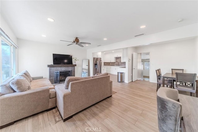 living room with ceiling fan, sink, and light wood-type flooring