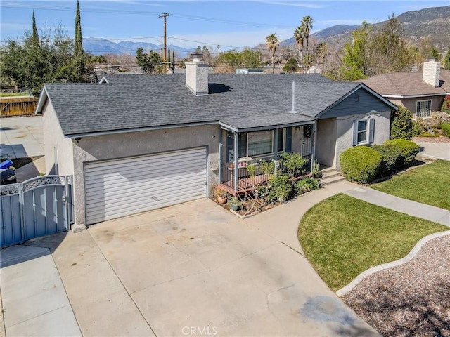 single story home with a garage, a mountain view, covered porch, and a front lawn