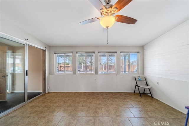 tiled spare room with a wealth of natural light and ceiling fan