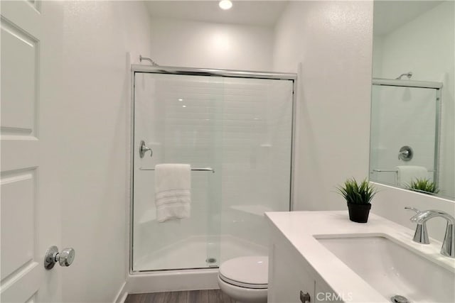 bathroom featuring toilet, a shower stall, wood finished floors, and vanity