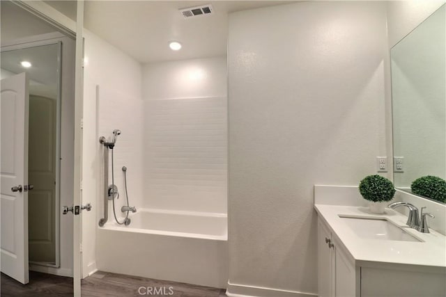 bathroom with shower / bath combination, visible vents, wood finished floors, and vanity