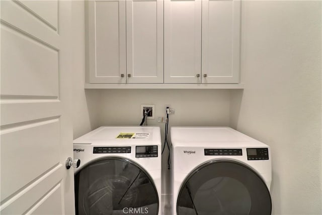 clothes washing area featuring cabinet space and washing machine and clothes dryer