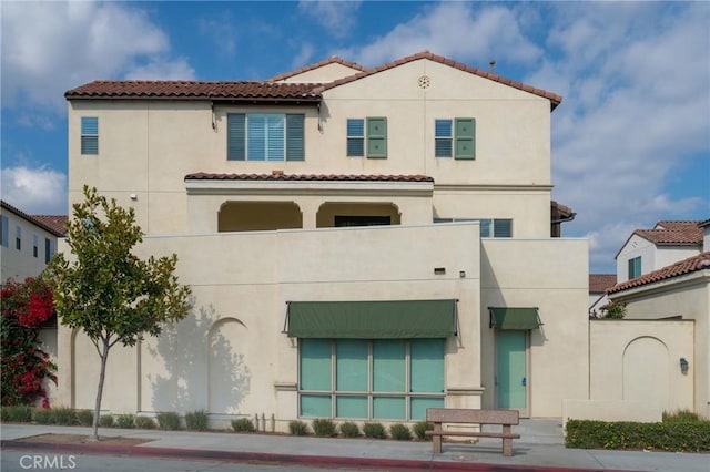 back of property featuring a tile roof and stucco siding