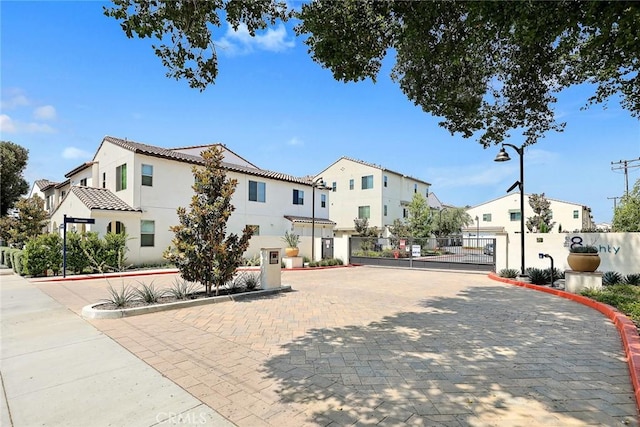 view of road featuring curbs, a gated entry, a gate, and a residential view