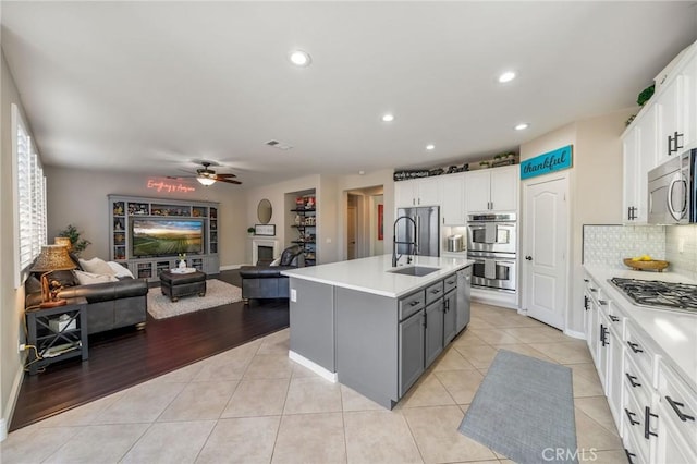 kitchen with a kitchen island with sink, white cabinetry, gray cabinets, and stainless steel appliances