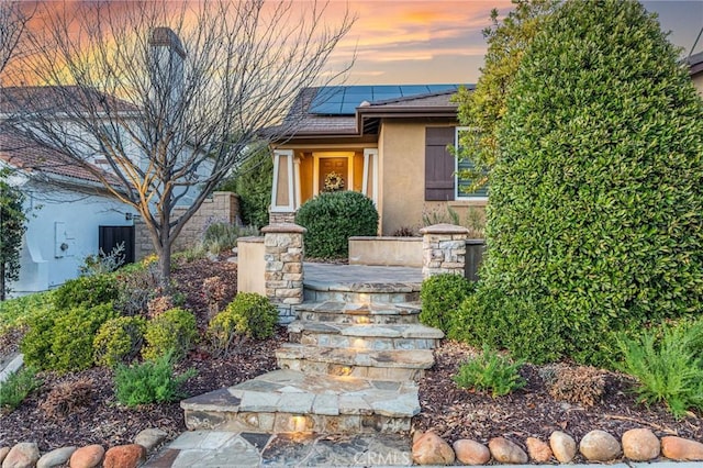 view of front of property with stucco siding and roof mounted solar panels