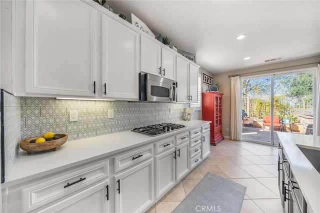 kitchen with white cabinetry, appliances with stainless steel finishes, backsplash, and light tile patterned floors