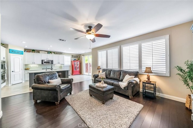 living room with dark wood-type flooring and ceiling fan