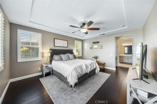 bedroom featuring dark hardwood / wood-style floors, a tray ceiling, and multiple windows