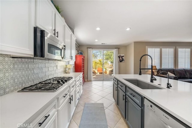 kitchen featuring sink, appliances with stainless steel finishes, backsplash, white cabinets, and light tile patterned flooring