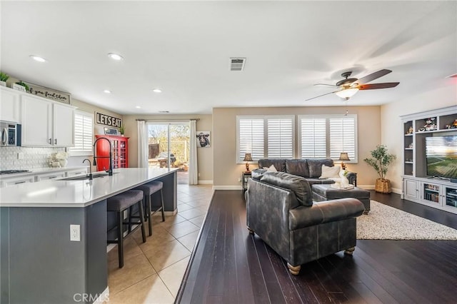 living room with ceiling fan, sink, and light wood-type flooring