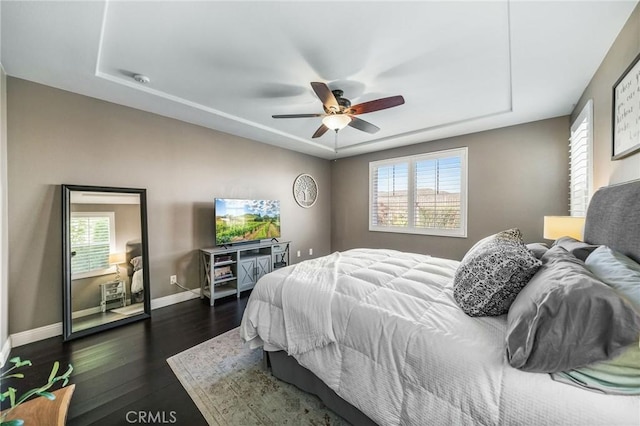 bedroom with a tray ceiling, dark hardwood / wood-style floors, and ceiling fan