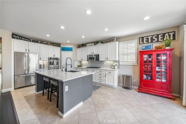 kitchen with an island with sink, white cabinetry, sink, a kitchen bar, and stainless steel appliances