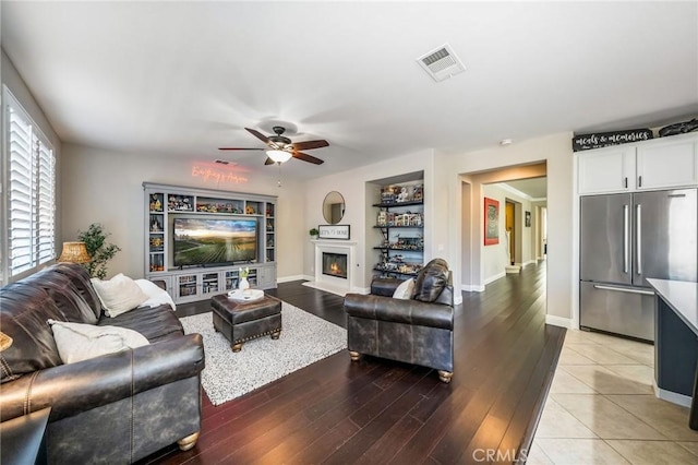 living room featuring wood-type flooring, ceiling fan, and built in shelves