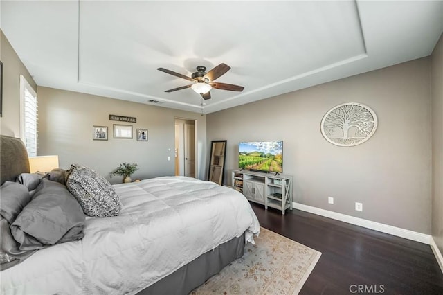 bedroom featuring a raised ceiling, ceiling fan, and dark hardwood / wood-style flooring