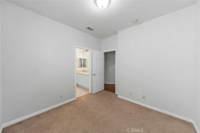 unfurnished bedroom with light colored carpet and ensuite bathroom