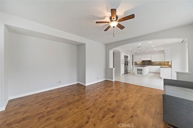 unfurnished living room featuring ceiling fan, sink, and light hardwood / wood-style floors