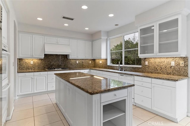 kitchen featuring white cabinetry, a center island, ventilation hood, and dark stone countertops