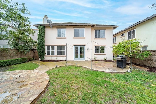 rear view of house with french doors, a lawn, and a patio area