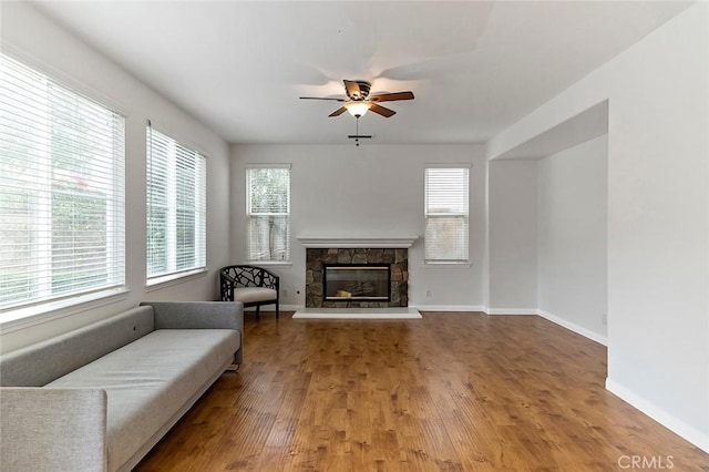 living room with ceiling fan, plenty of natural light, a fireplace, and hardwood / wood-style floors