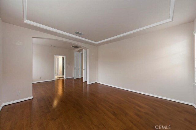 unfurnished room featuring a tray ceiling and dark hardwood / wood-style floors