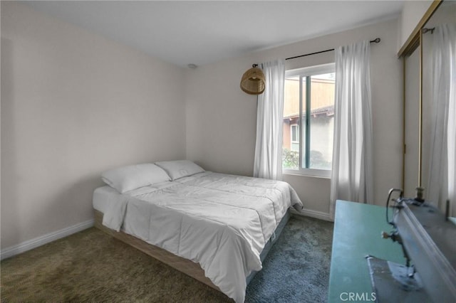 bedroom with dark colored carpet and baseboards