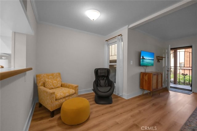 living area with crown molding, baseboards, and wood finished floors