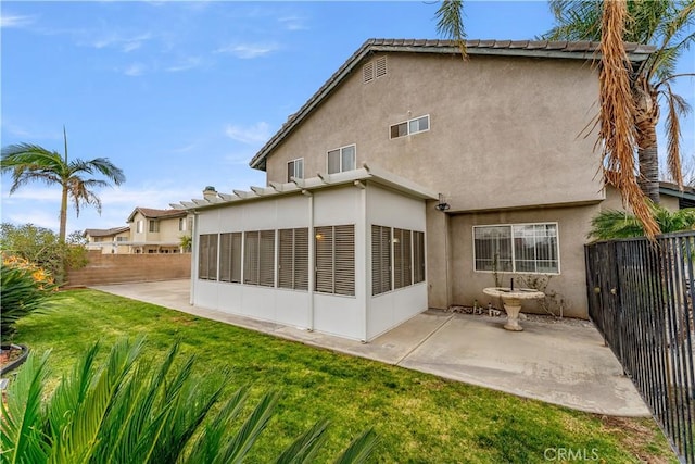 back of house featuring a lawn, a sunroom, and a patio area