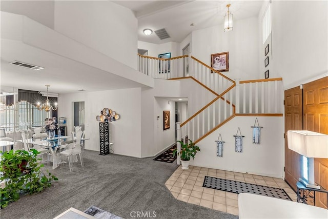 entryway featuring light colored carpet, a wealth of natural light, a notable chandelier, and a high ceiling