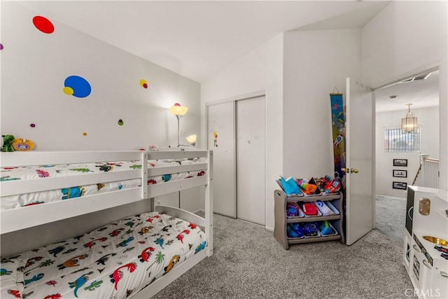 carpeted bedroom with lofted ceiling, a notable chandelier, and a closet