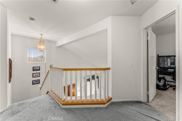 hallway featuring carpet flooring and a notable chandelier