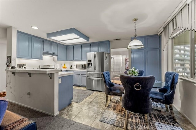 kitchen with hanging light fixtures, a kitchen bar, stainless steel appliances, blue cabinets, and kitchen peninsula