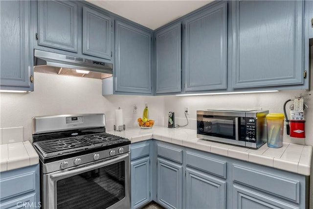 kitchen featuring blue cabinets, tile countertops, and appliances with stainless steel finishes