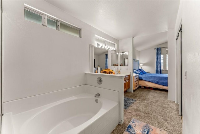 bathroom with vanity and tiled bath