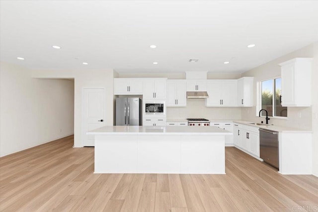 kitchen featuring a kitchen island, appliances with stainless steel finishes, white cabinets, and light wood-type flooring