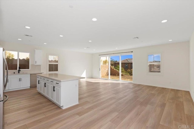 kitchen with white cabinetry, light hardwood / wood-style floors, appliances with stainless steel finishes, and a kitchen island