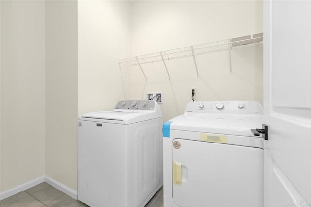 clothes washing area with washing machine and dryer and light tile patterned flooring