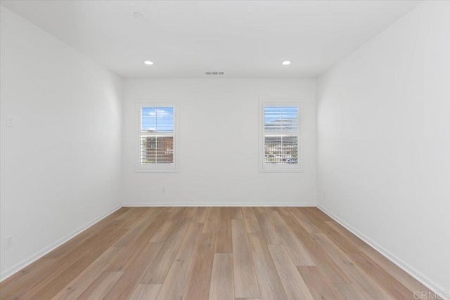 spare room with plenty of natural light and light hardwood / wood-style flooring