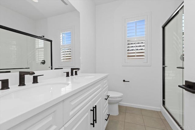 bathroom featuring tile patterned floors, toilet, a shower with door, and vanity