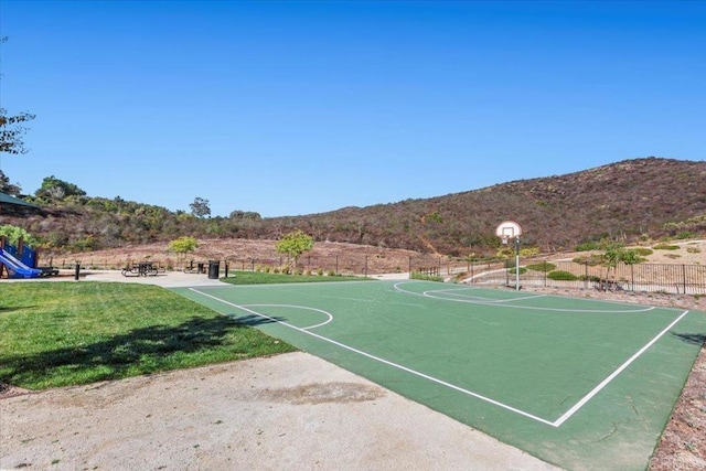 view of sport court with a mountain view and a lawn