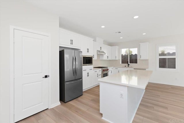 kitchen with a kitchen island, white cabinetry, sink, light hardwood / wood-style floors, and stainless steel appliances